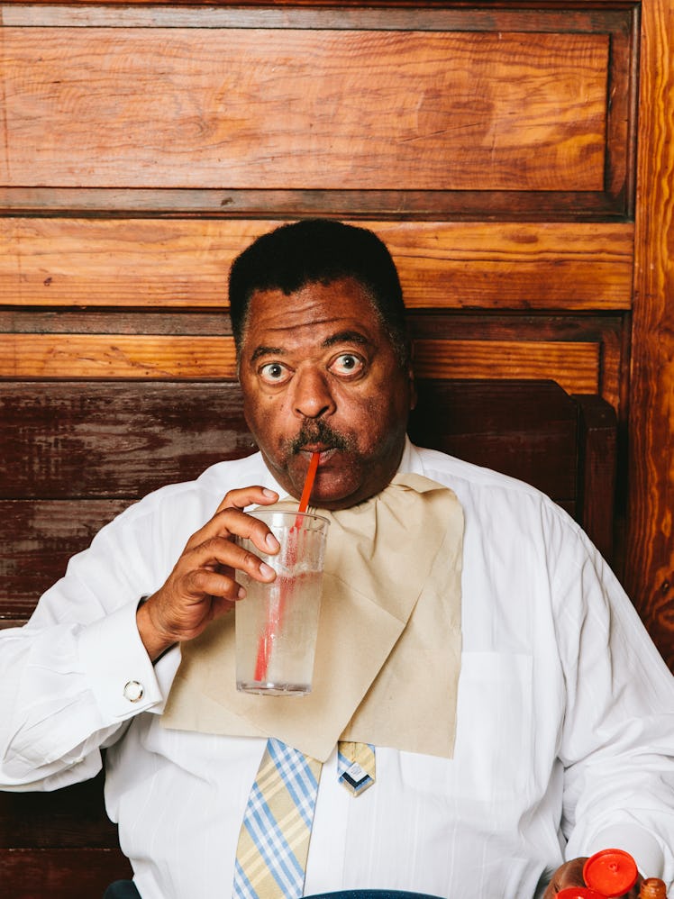 Sammy Stephens drinking soda from the glass with a red straw while wearing a white shirt 
