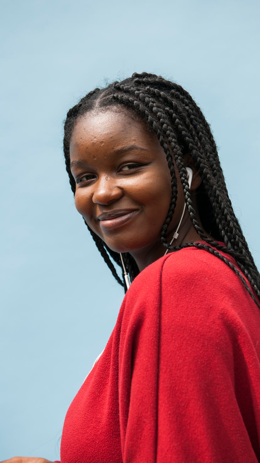 Young woman smiling in a red sweater on the luckiest day in November 2022 for every zodiac sign.