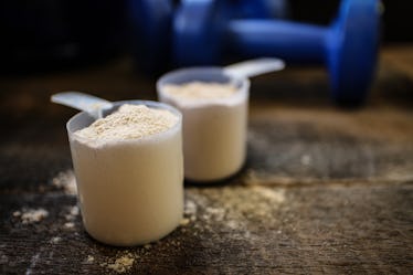 Scoops of pre-workout powder on a wooden table with weights behind it.