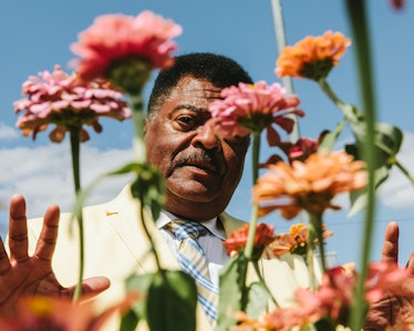 Sammy Stephens standing behind orange and pink flowers