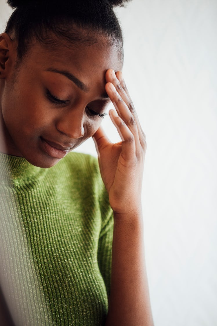 Young woman with a headache after reading her October 31, 2022 weekly horoscope.