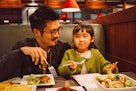 父亲和小女儿一起在餐厅吃饭时面带微笑