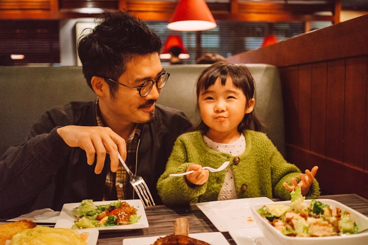 Father and young daughter smiling as they eat together in a restaurant