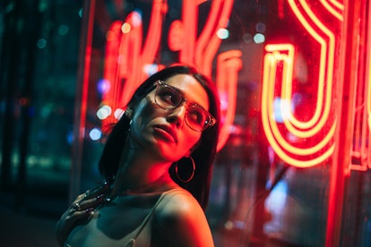 Young woman in neon lights after reading her November 2022 horoscope