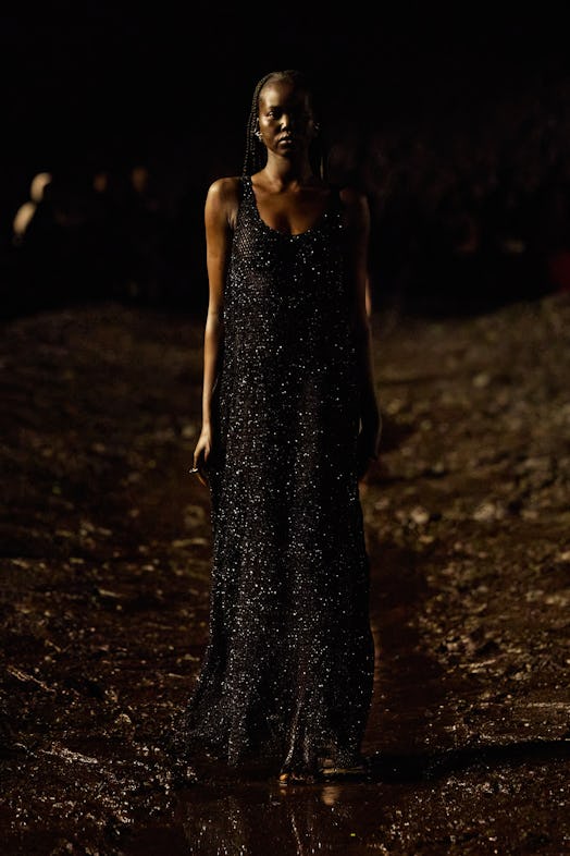A female model in a black sequin dress walking the mud Balenciaga show 