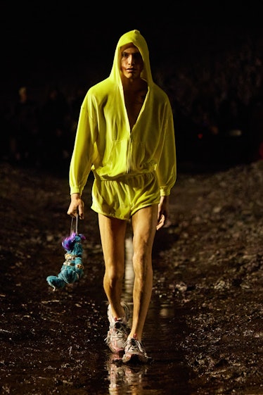 A male model walking the mud Balenciaga show in a yellow hoodie