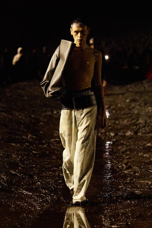 A male model walking the mud Balenciaga show in a grey blazer and yellow pants