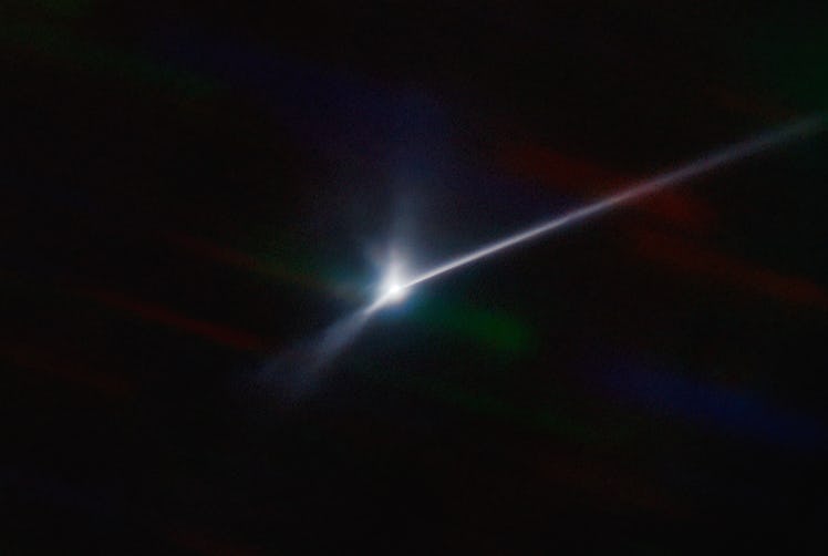 A bright point of light with a curved, bright streak extending off to the right, on a black backgrou...
