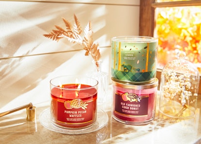 candles stacked on a pile of books in an article about Bath & Body Works Fall Candle Instagram Capti...