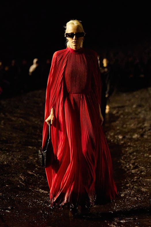 A female model walking the mud Balenciaga show in a red overall dress
