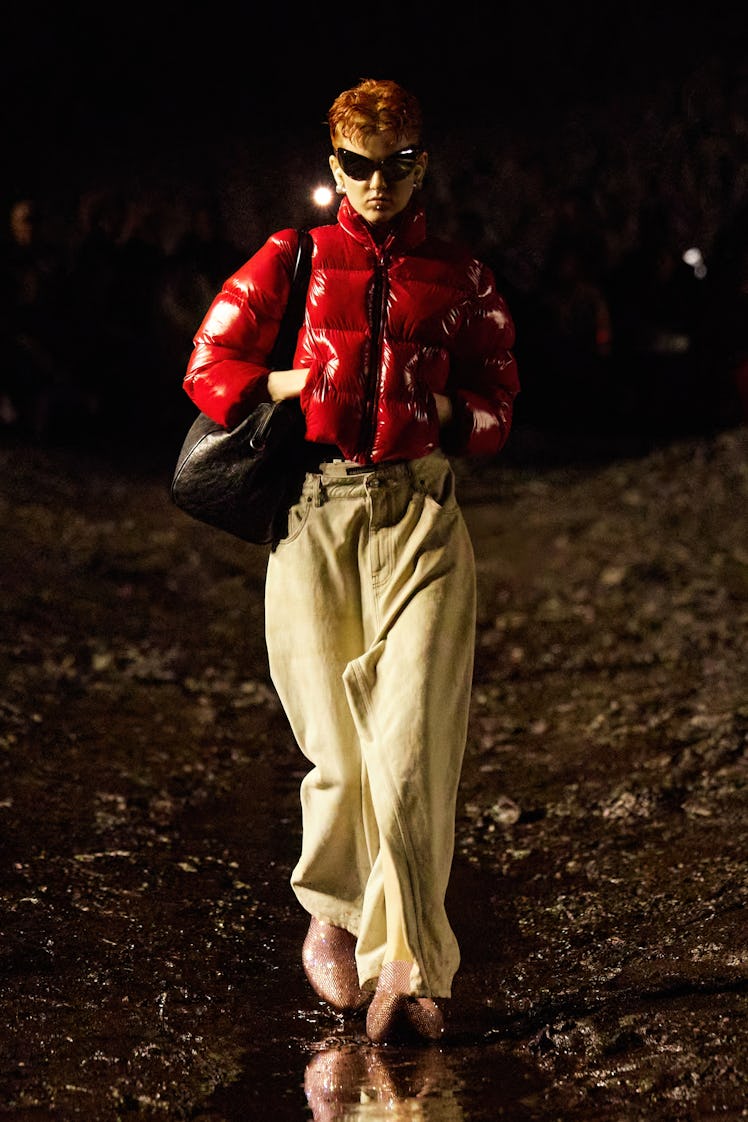 A model wearing Balenciaga sunglasses, red puffer jacket and nude loose jeans at Paris Fashion Week ...