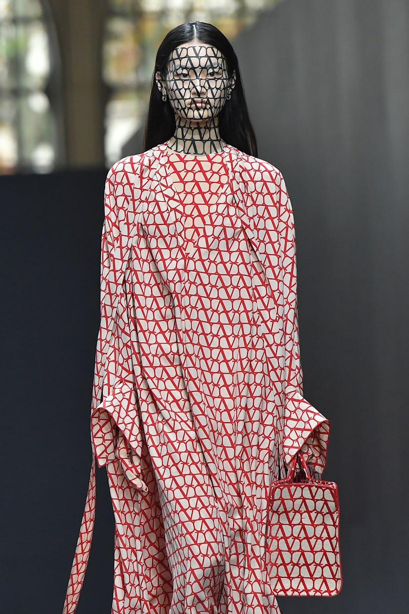 A model walking the runway at Valentino, their face covered in Valentino 'V's