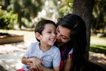 A mom and her autistic son laughing in a park.