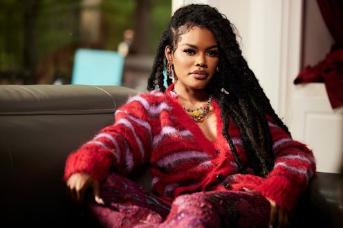 Teyana Taylor in a red and purple striped cardigan and chunky jewelry sitting down for an interview