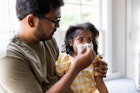 一位父亲用纸巾给生病的女儿擤鼻涕。