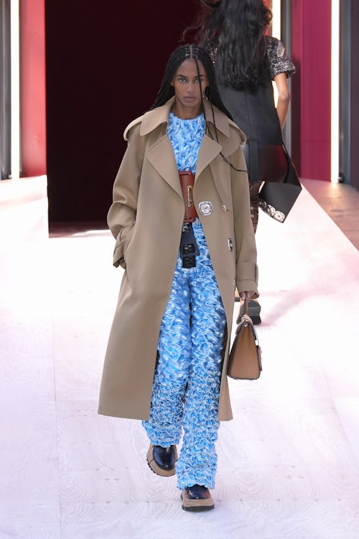 A model in a matching blue top and pants and beige coat at the Louis Vuitton Spring 2023 Paris Fashi...