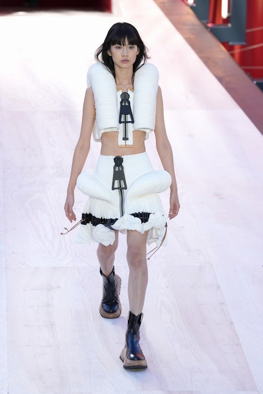 A model in a white top and skirt with oversize zippers at the Louis Vuitton Spring 2023 Paris Fashio...