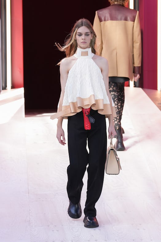 A model in a white frilled top and black pants at the Louis Vuitton Spring 2023 Paris Fashion Week