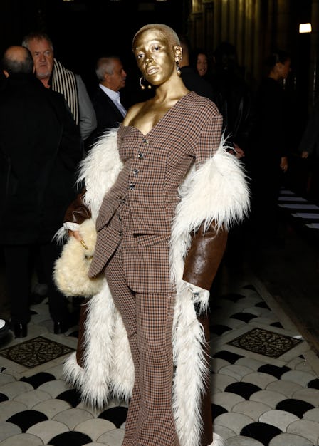 A gold-covered Doja Cat wearing a plaid suit and fuzzy coat