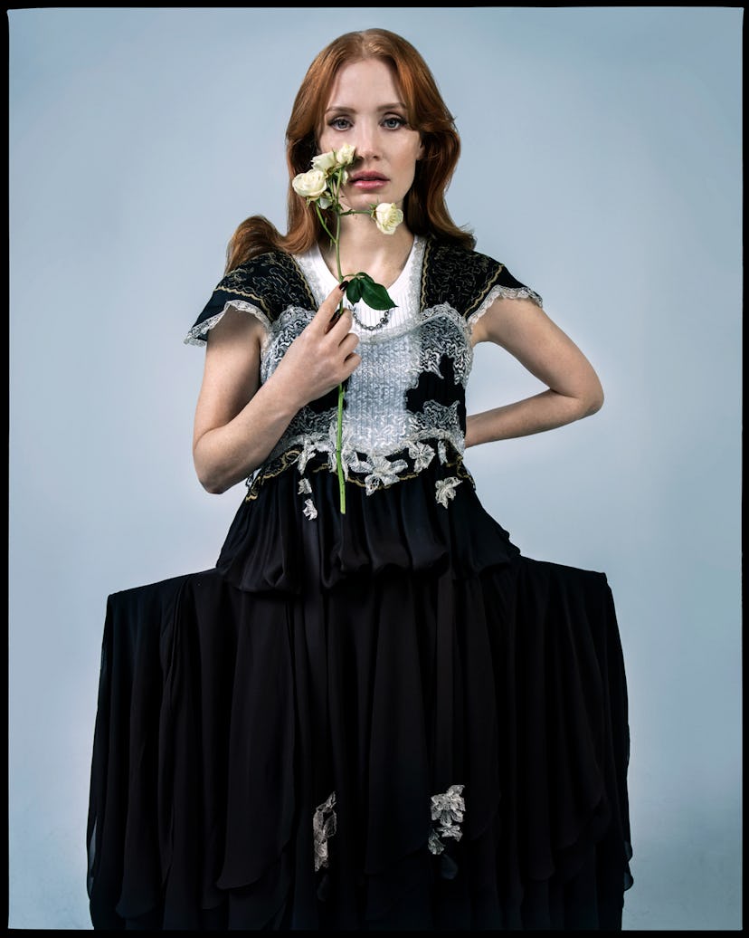 Jessica Chastain posing while holding a white flower next to her face