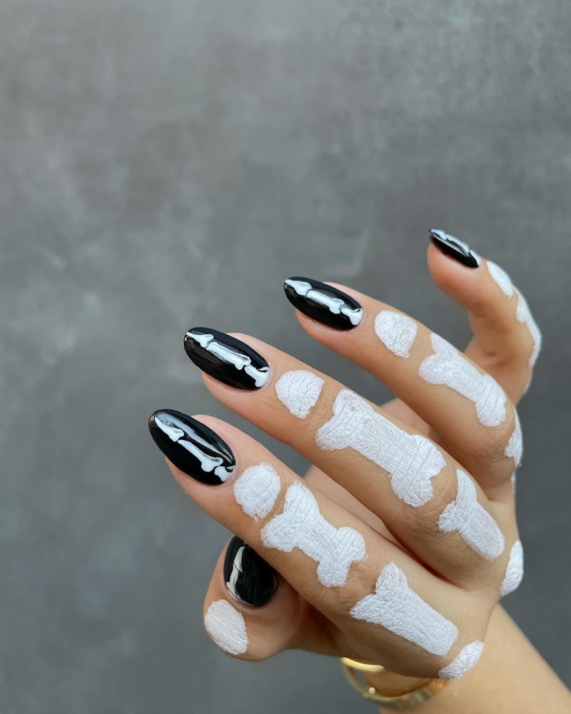 Want a simple and classy design idea for black Halloween nails? This minimal bone print is perfect.