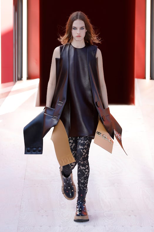 A model in a black dress and oversized leather waistcoat at the Louis Vuitton Spring 2023 Paris Fash...