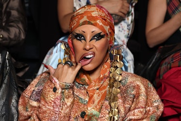 Doja Cat wearing dramatic black eye makeup and putting her finger in her mouth at Paris Fashion Week