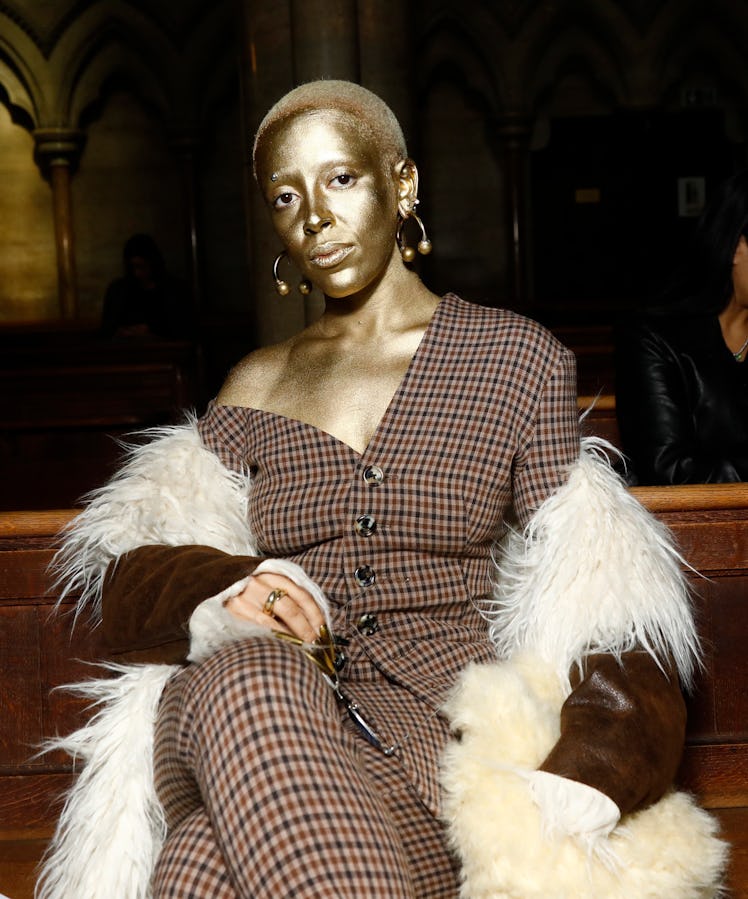 A gold-covered Doja Cat wearing a plaid suit and fuzzy jacket