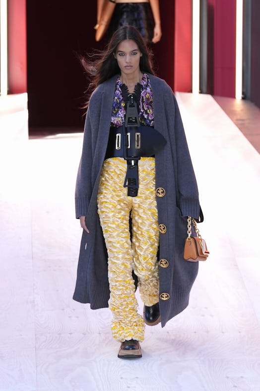 A model in a floral top, a grey sweater, and yellow pants at the Louis Vuitton Spring 2023 Paris Fas...