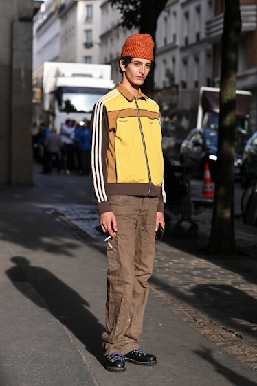 A model is seen wearing an Adidas jacket, brown pants, black shoes and orange beanie outside the Lan...