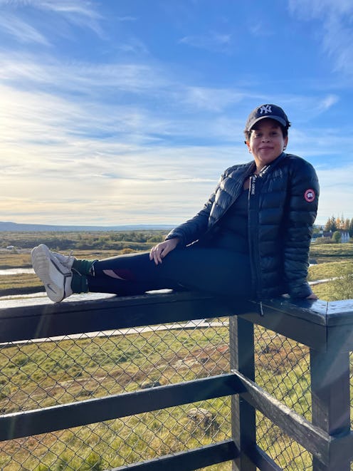 Natasha Marsh sitting on a fence on a sunny day wearing canada goose outwear
