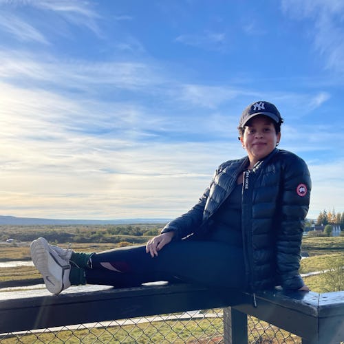 Natasha Marsh sitting on a fence on a sunny day wearing canada goose outwear