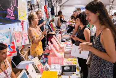 People lined up at a row of tables with books at the NY Art Book Fair