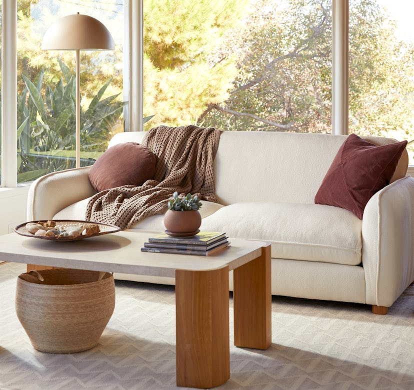 A living room with Parachute furniture, a beige couch with brown pillows, a beige-brown coffee table...