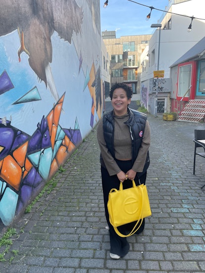 Natasha Marsh walking while holding a yellow handbag and wearing a canada goose vest