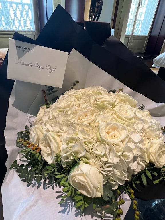 A bouquet of white roses lying next to a note that says "Mademoiselle Maggie Rogers