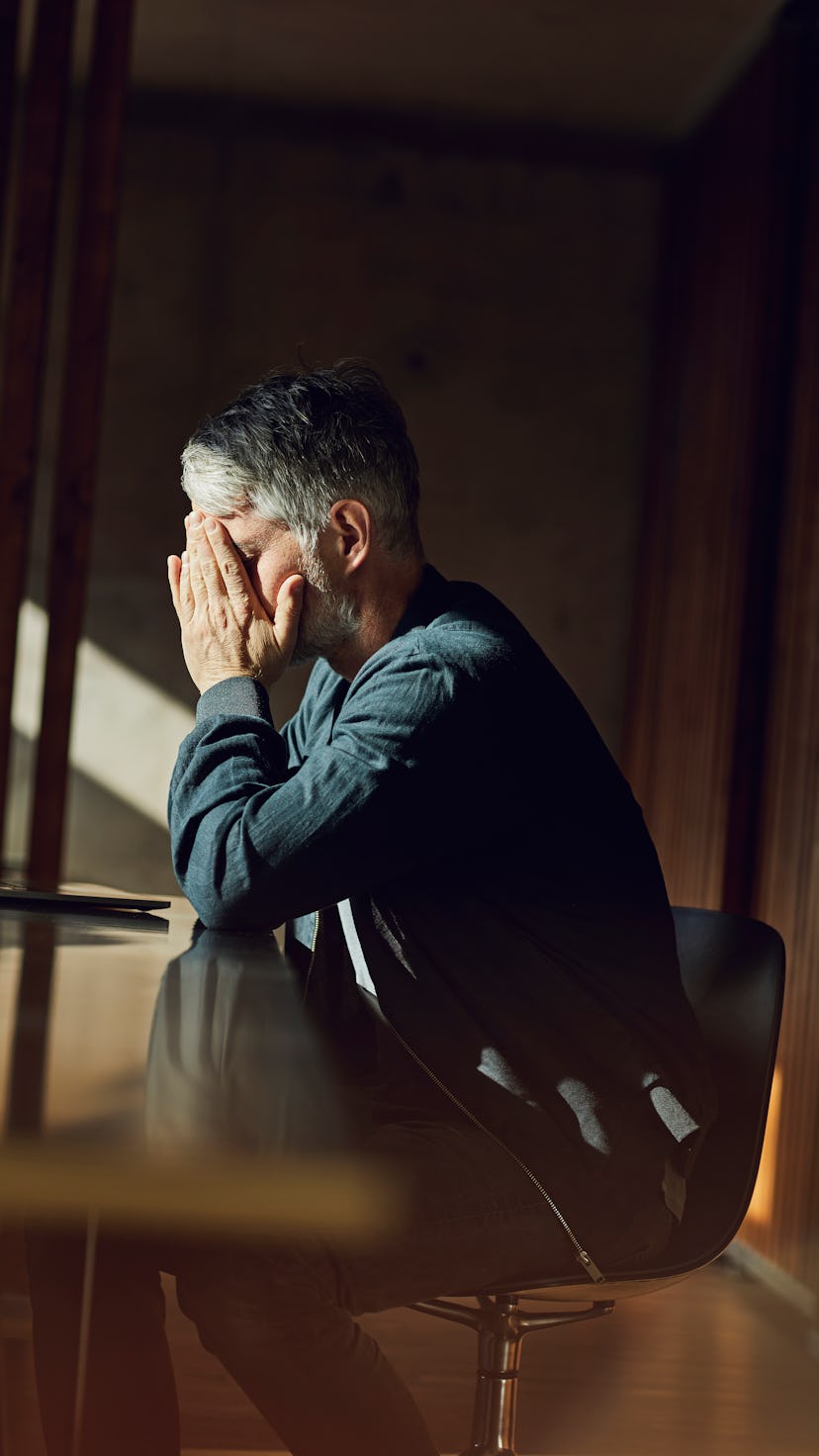 A man at his desk with his face in his hands.