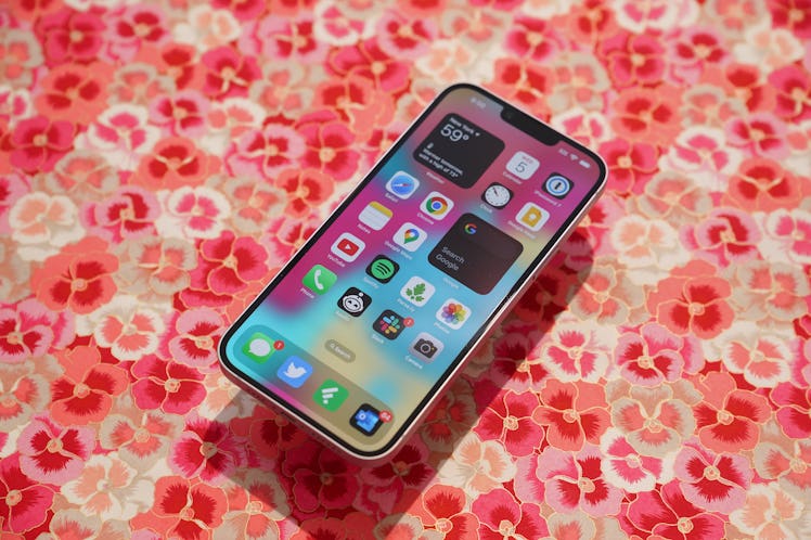 An iPhone 14 Pro Max on a table with a floral table cloth 