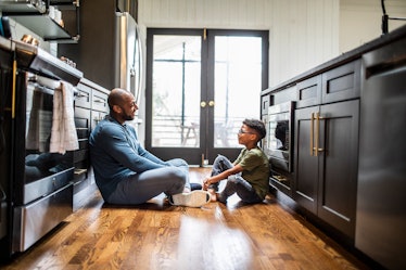 A dad sitting with his son on the kitchen floor, setting up family rules.