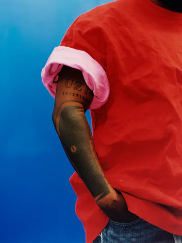 Kendrick Lamar wearing a Balenciaga red shirt, blue jeans.