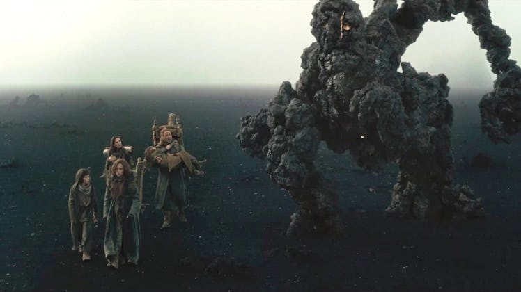 Humans looking up at a giant rock monster known as a Watcher in Noah 