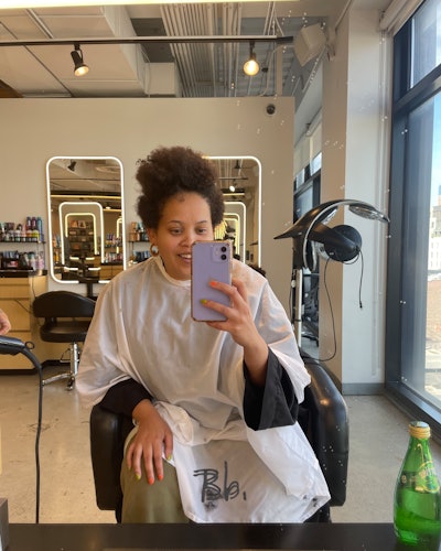 Natasha Marsh taking a selfie in a hair salon.