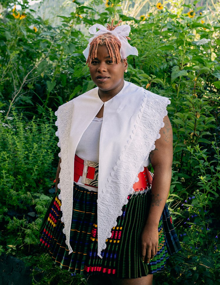 the artist Precious Okoyomon wearing a Simone Rocha top and Chopova Lowena belted skirt in front of ...