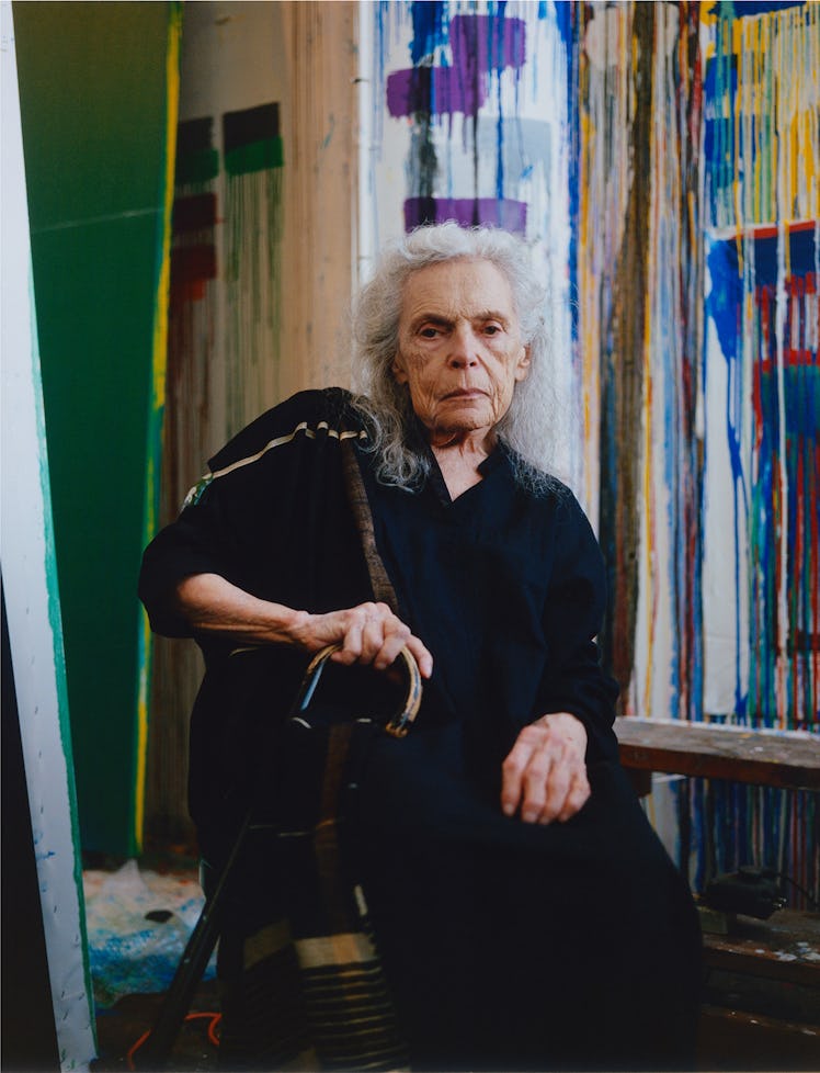 the painter pat steir in front of a rainbow of abstract canvases