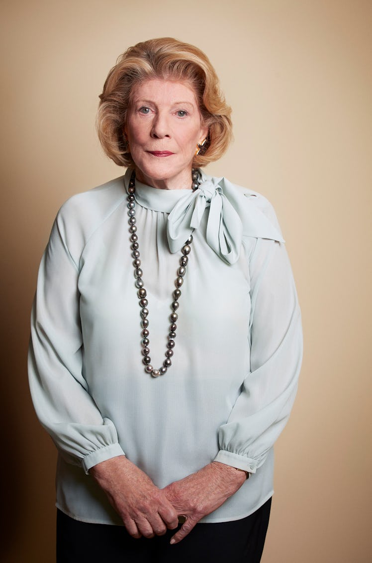 the philanthropist agnes gund wearing a light blue blouse and black pearls, looking pensively into t...