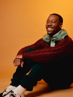 A red jacket and white sweater trending outfit worn by Tyler James Williams