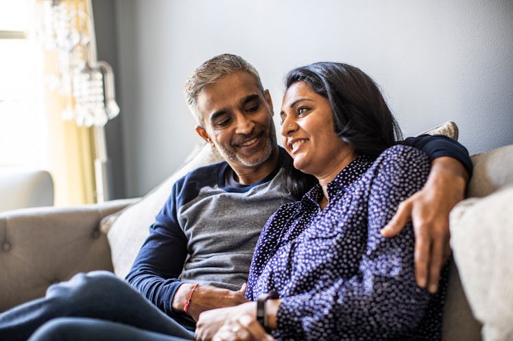 Husband sitting on the couch while hugging his wife 