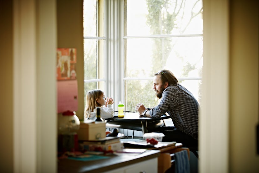Dad and young daughter talking at table
