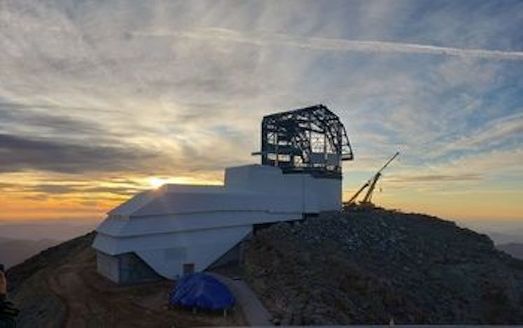 a large observatory on a hill with the sun and clouds in the background