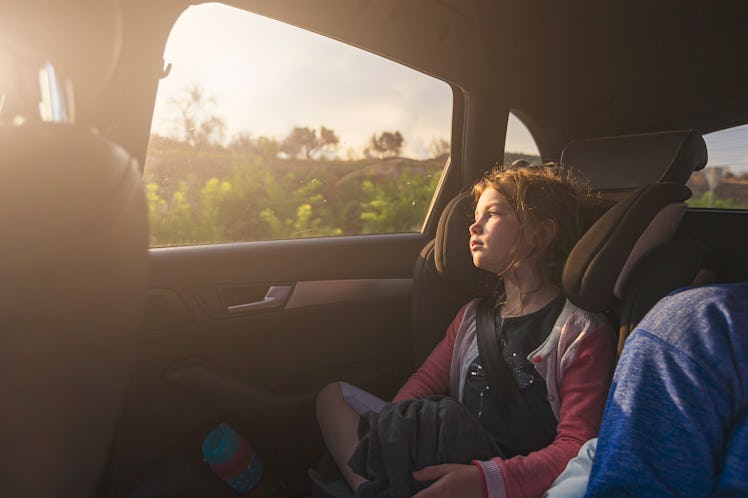 A carsick child sitting in the back seat of a car.